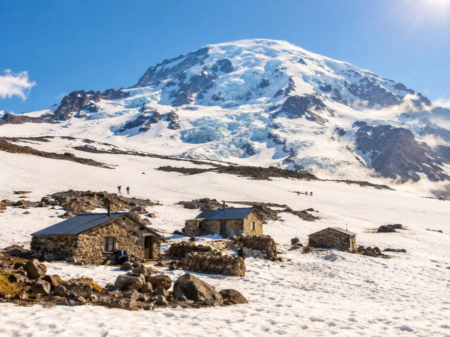 The stone huts of Camp Muir on a snowfield below the upper mountain