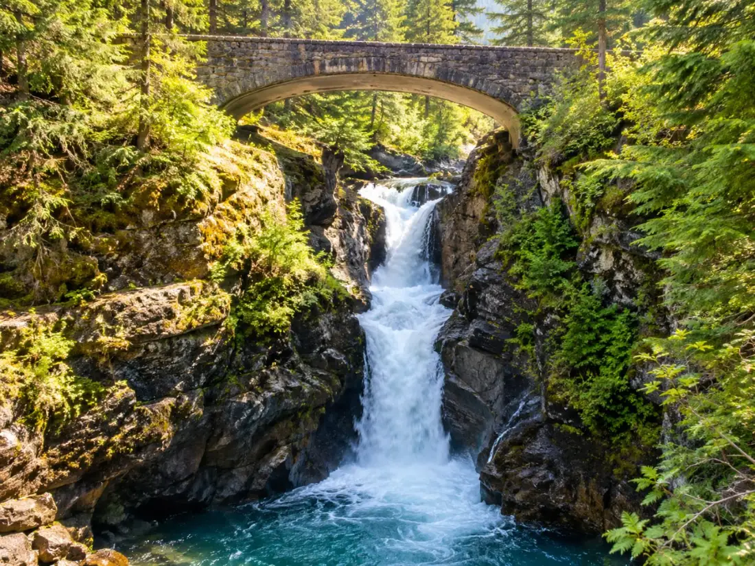 Die Christine Falls fallen unter einer alten Steinbrücke im Wald hinab