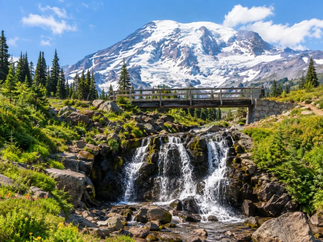 Die Myrtle Falls stürzen über dunklen Fels unterhalb des verschneiten Mount Rainier